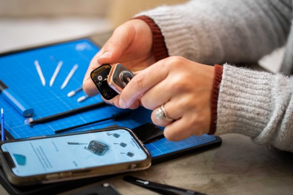 Hands opening up an Apple Watch over a smartphone with instructions